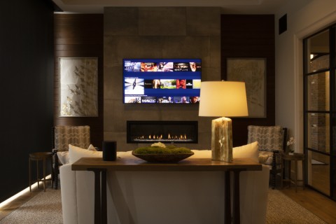 Dimly lit living room with a fireplace and wall-mounted TV displaying content.