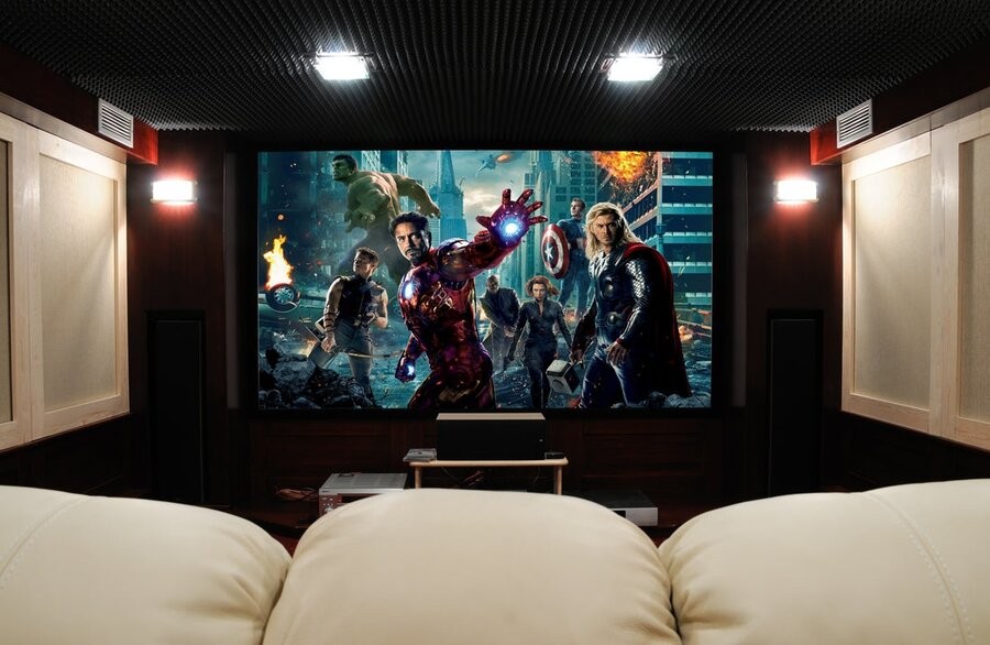 A home cinema design featuring comfy seating, acoustic paneling, and a large display showing The Avengers (2012) on the screen.