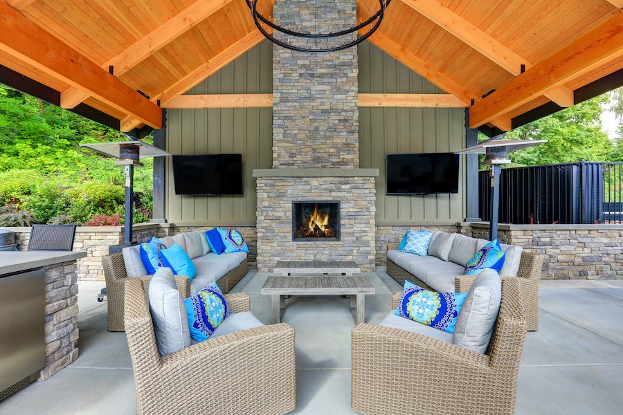 Covered patio with furniture, dual TVs and fire place.