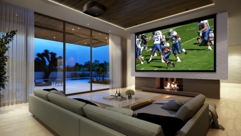 Large projection screen image of football players in a living room with low seating and floor-to-ceiling windows