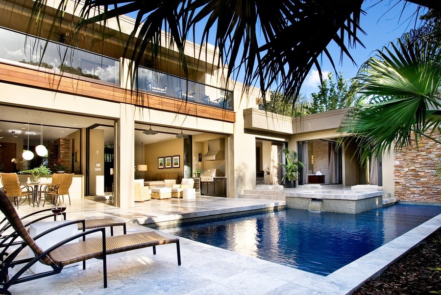 outdoor entertainment space featuring a pool, lanai, lounge furniture and palm trees.