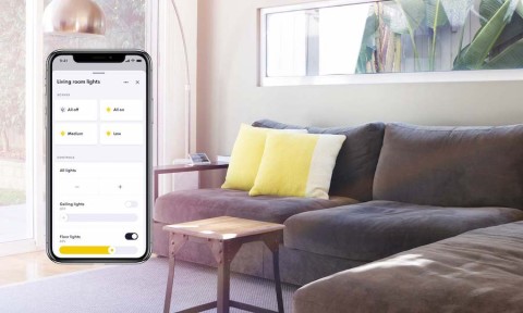 Living room couch and side table situated behind a superimposed Crestron Home app interface.