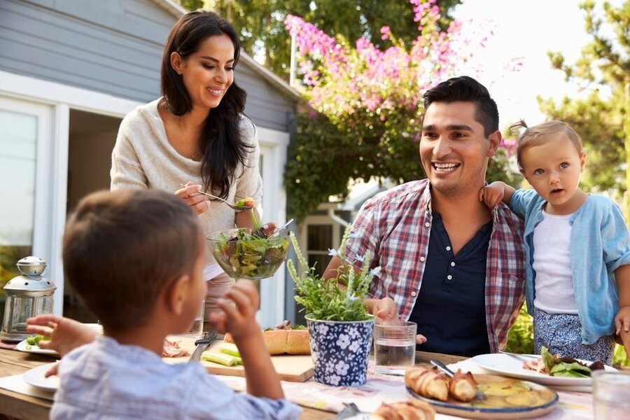 A family gathering outside in their backyard at a table.