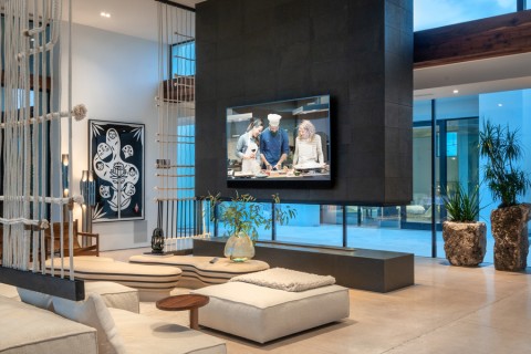 high-end living room with wall-mounted TV in front of floor-to-ceiling windows and sectional sofas