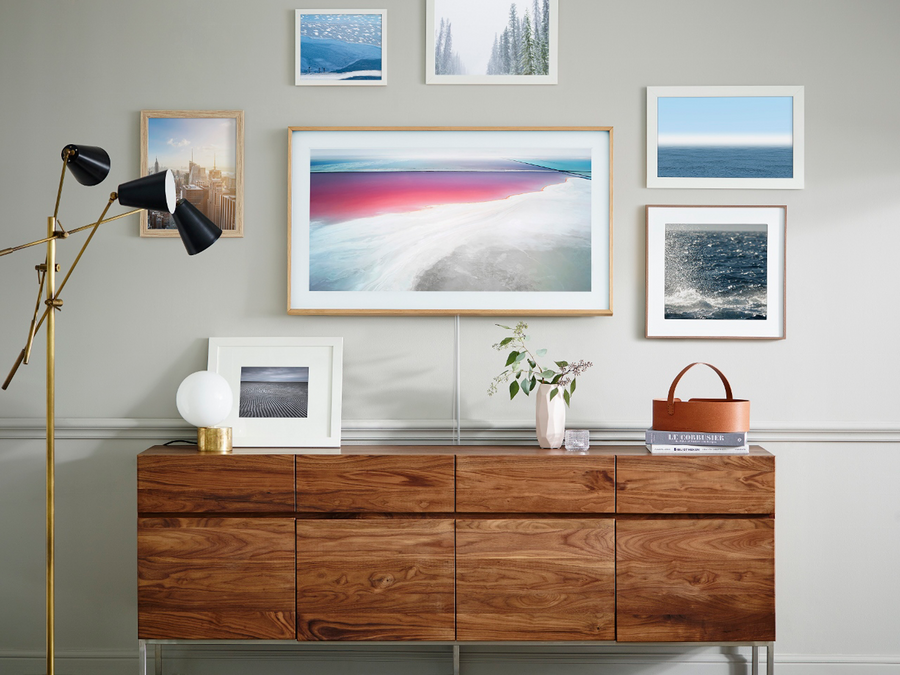 A Samsung Frame TV is mounted among several framed pieces of artwork