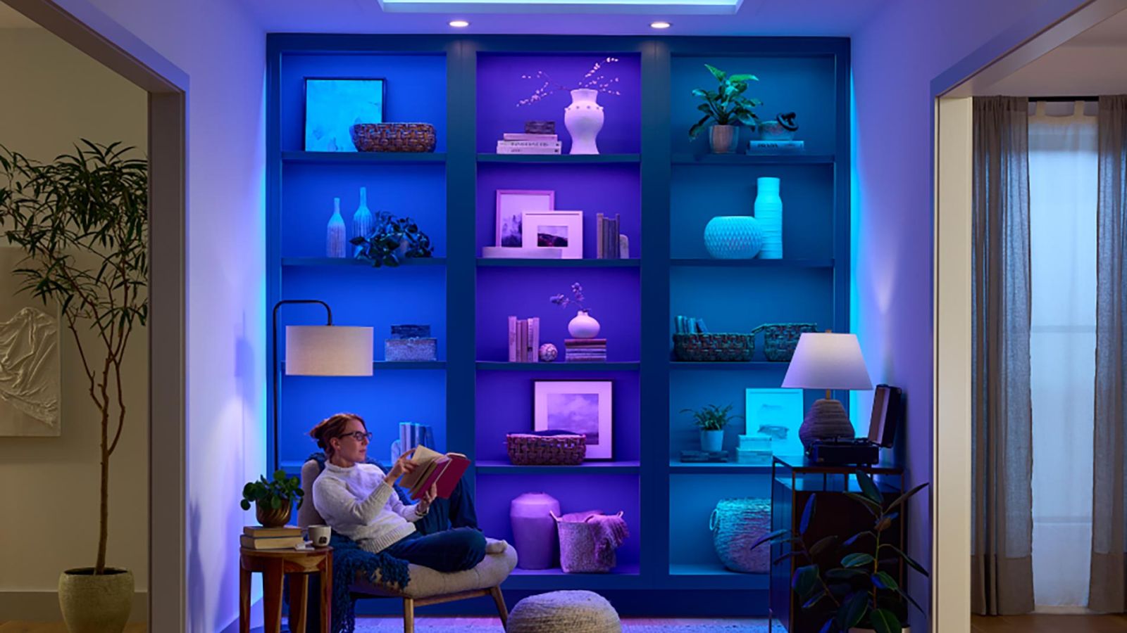 Woman reading in room with colorful LED shelf lighting and soft furniture